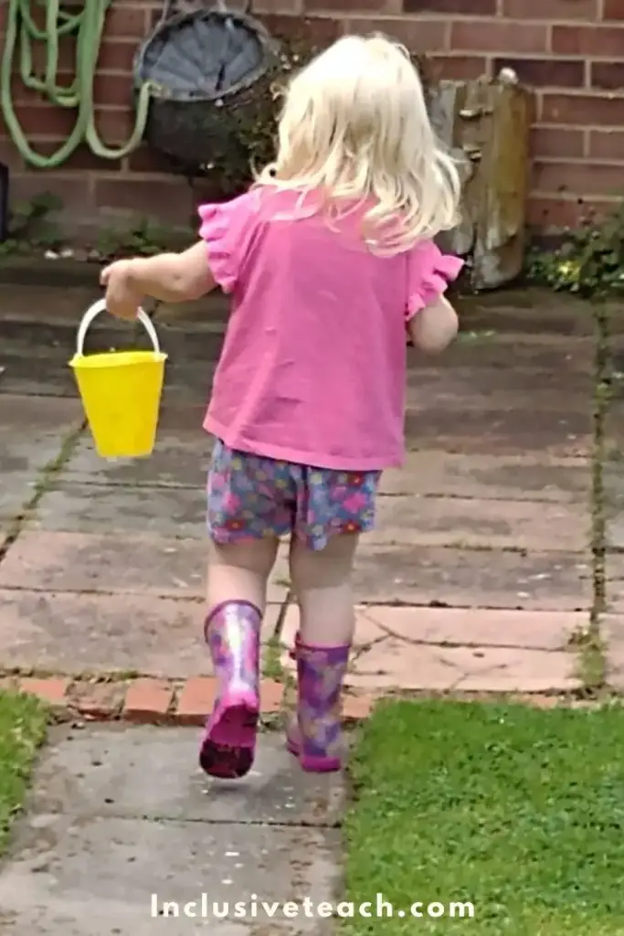 Water Play Activity Developing Gross Motor skills. Little Girl carrying a bucket
